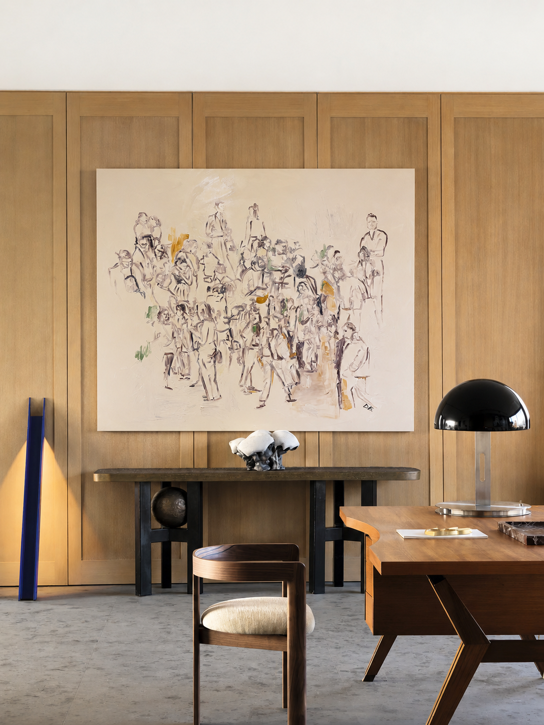 Modern office interior with wooden furniture, abstract artwork, and a lamp.
